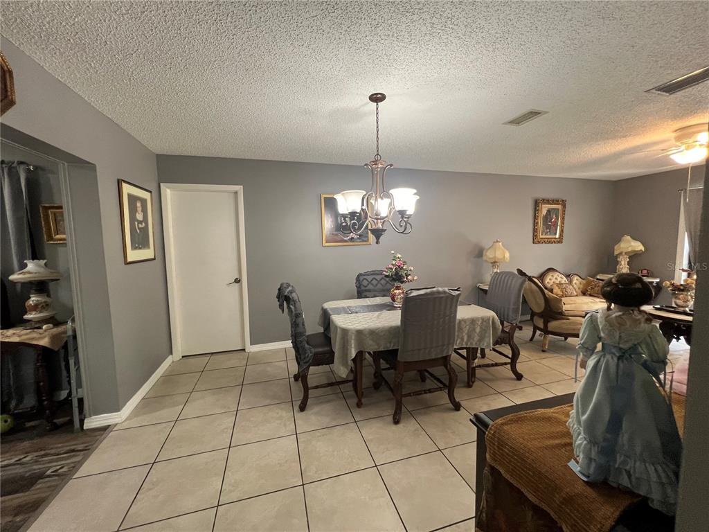 A dining area with tile flooring, a chandelier, and a table with four chairs — 220 NE 11TH STREET, CRYSTAL RIVER, FL
