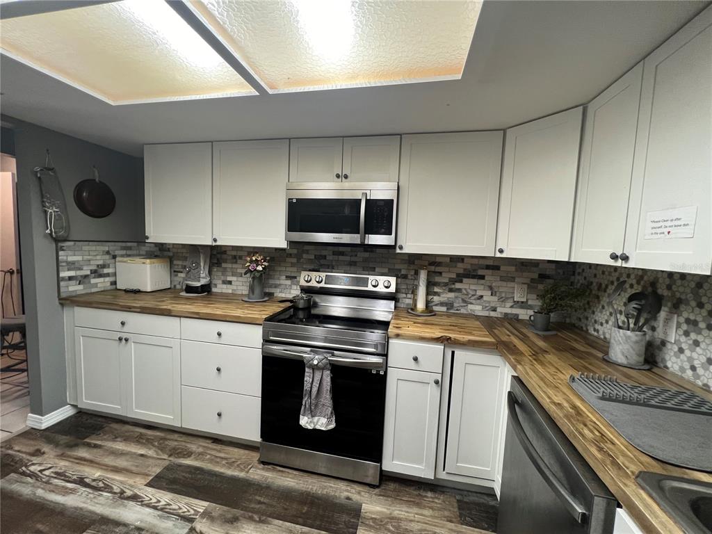 A kitchen features white cabinets, a stainless steel stove, and wood-look countertops — 220 NE 11TH STREET, CRYSTAL RIVER, FL