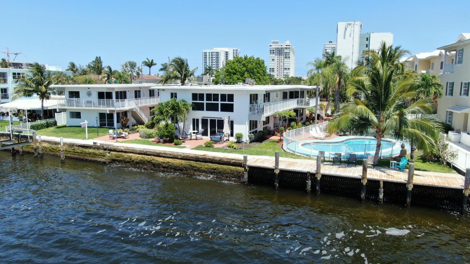 An aerial view of a white waterfront apartment building with a pool and wooden dock — 1001 S Riverside Drive # 104, Pompano Beach FL 33062, POMPANO BEACH, FL