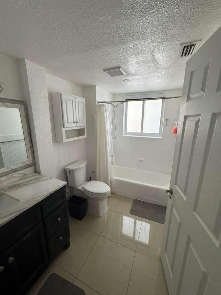 A bathroom features a dark vanity, a white toilet, and a shower-tub combination — 1001 S Riverside Drive # 104, Pompano Beach FL 33062, POMPANO BEACH, FL