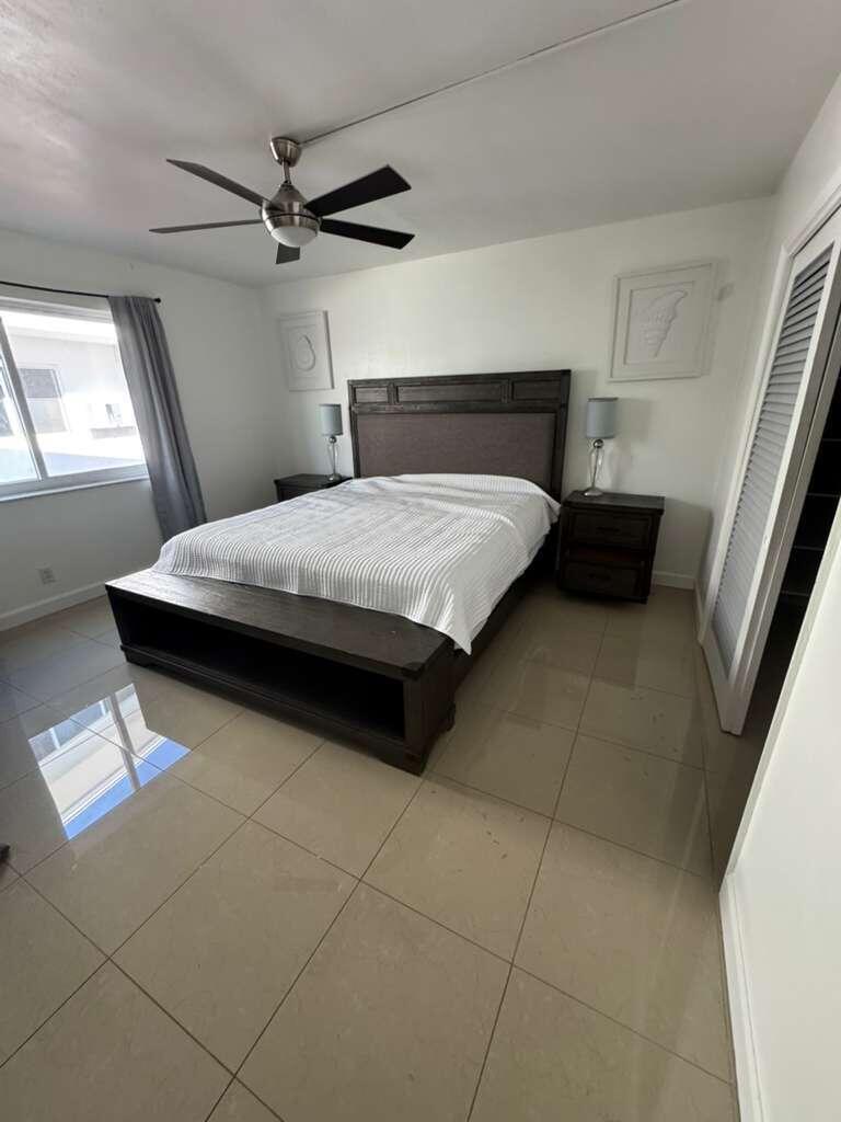 A bedroom features a dark wood bed frame, tile flooring, and a ceiling fan — 1001 S Riverside Drive # 104, Pompano Beach FL 33062, POMPANO BEACH, FL