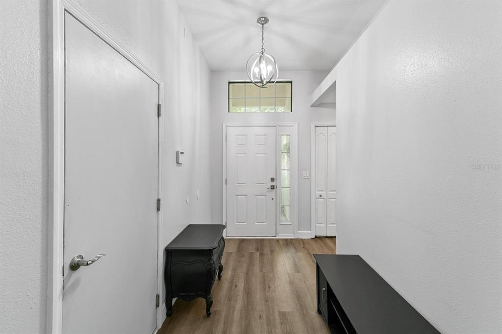An entryway features light wood-look flooring, white walls, a high ceiling, and a pendant light — 1365 SHOOTINGSTAR LANE, ST JOHNS, FL