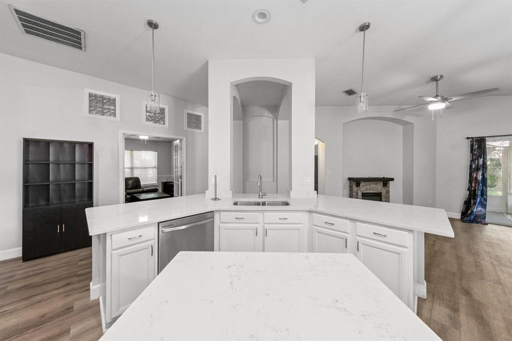 A kitchen features a white island, quartz countertops, white cabinetry, and stainless steel appliances — 1365 SHOOTINGSTAR LANE, ST JOHNS, FL