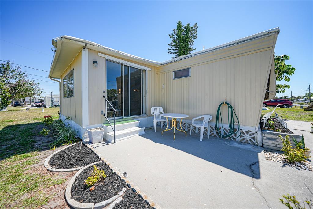 The exterior of a mobile home features a concrete patio, sliding glass doors, and landscaping — 1407 SEAGULL DRIVE, ENGLEWOOD, FL