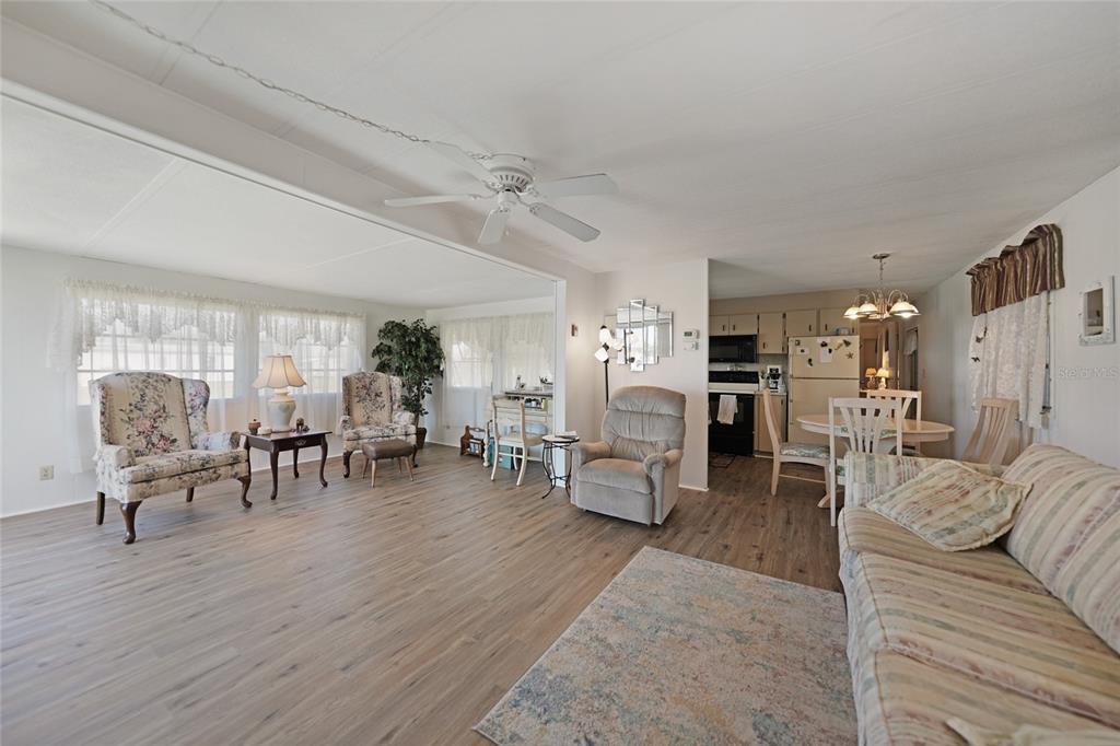 An open-concept living and dining area features wood-look flooring, a ceiling fan, and neutral walls — 1407 SEAGULL DRIVE, ENGLEWOOD, FL