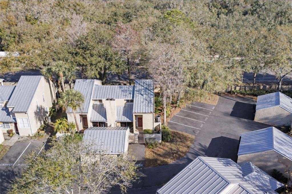 An aerial view shows several multi-story townhomes with metal roofs and adjacent paved parking spaces — 3401 CYPRESS HEAD COURT, TAMPA, FL