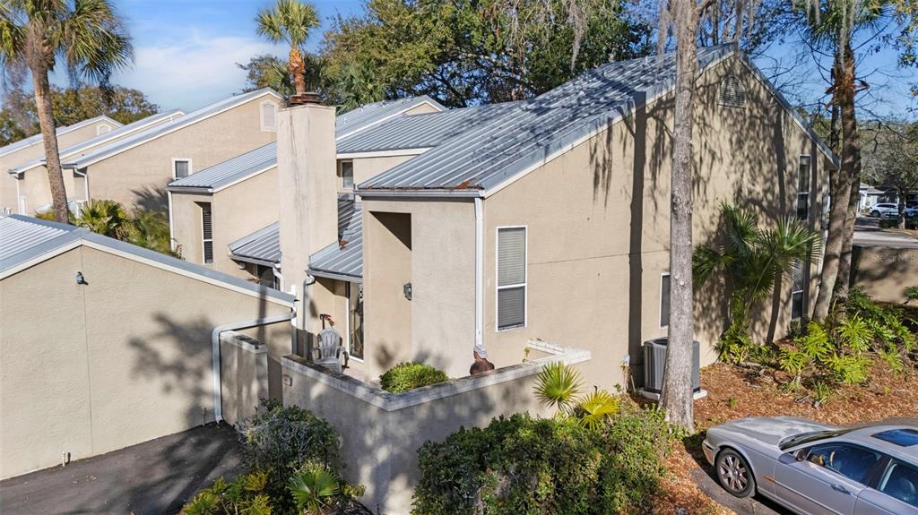 An exterior view of a tan stucco townhouse with a metal roof and chimney — 3401 CYPRESS HEAD COURT, TAMPA, FL