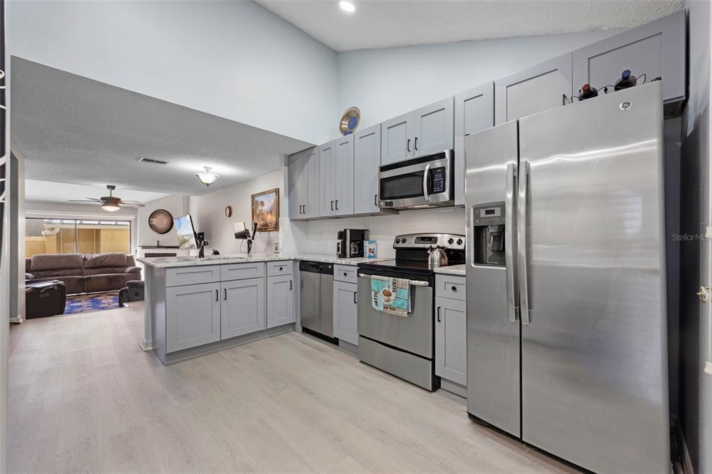 A kitchen with gray cabinets, stainless steel appliances, and light wood-look flooring — 3401 CYPRESS HEAD COURT, TAMPA, FL