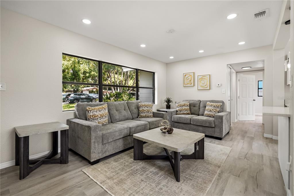 A living room features gray sofas, a matching coffee table, and light wood-look flooring — 2601 HEALY DRIVE, ORLANDO, FL