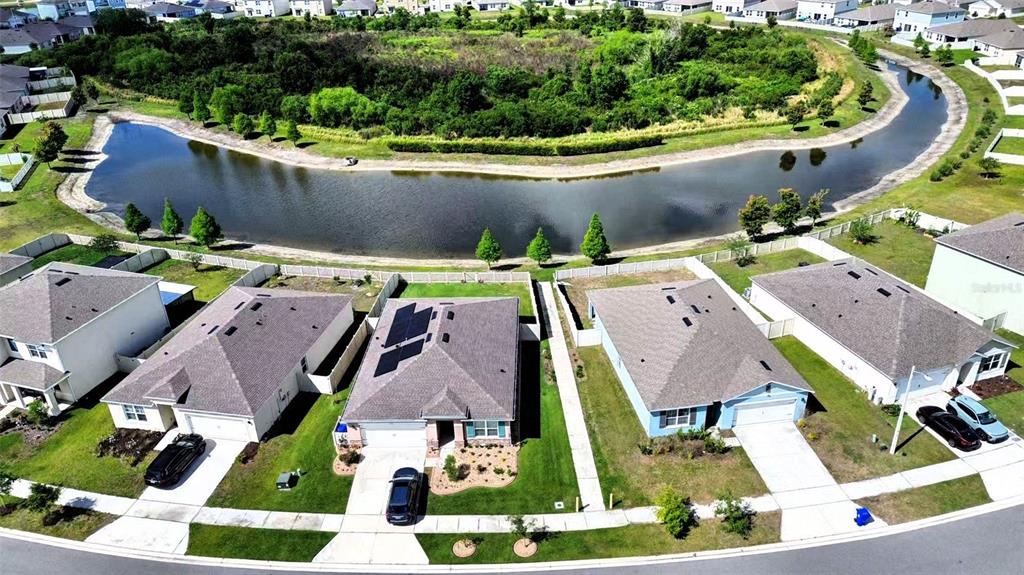 An aerial view shows suburban houses with driveways situated along a curved retention pond — 5567 SILTSTONE STREET, LAKELAND, FL