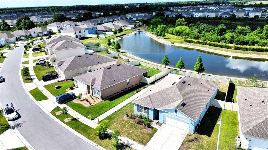 An aerial view shows suburban houses with driveways and lawns bordering a retention pond — 5567 SILTSTONE STREET, LAKELAND, FL