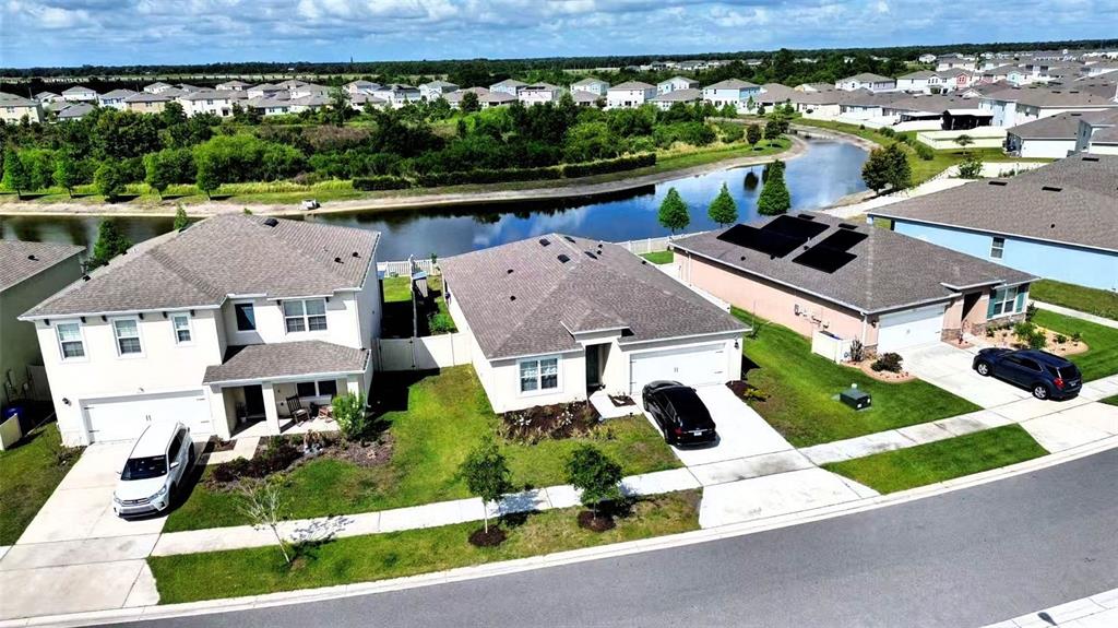 An aerial view shows three suburban houses with driveways and a pond in the background — 5567 SILTSTONE STREET, LAKELAND, FL