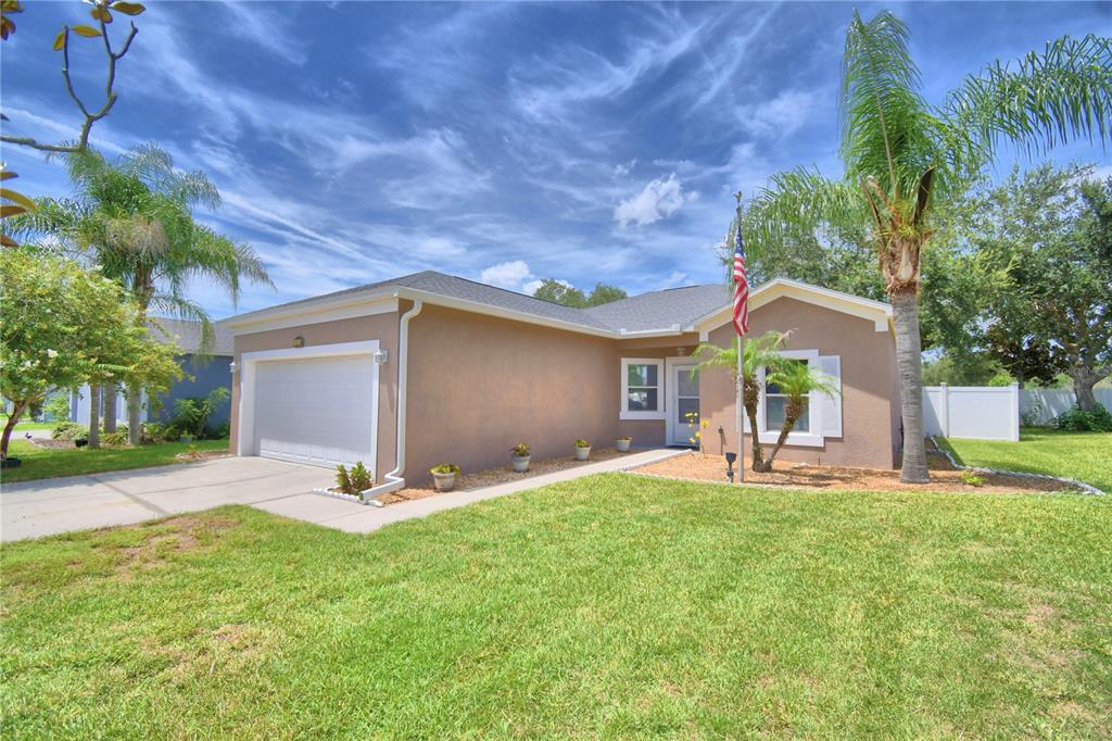 A single-story house with a tan stucco exterior, a one-car garage, and a front lawn — 5621 FOREST RIDGE DRIVE, WINTER HAVEN, FL