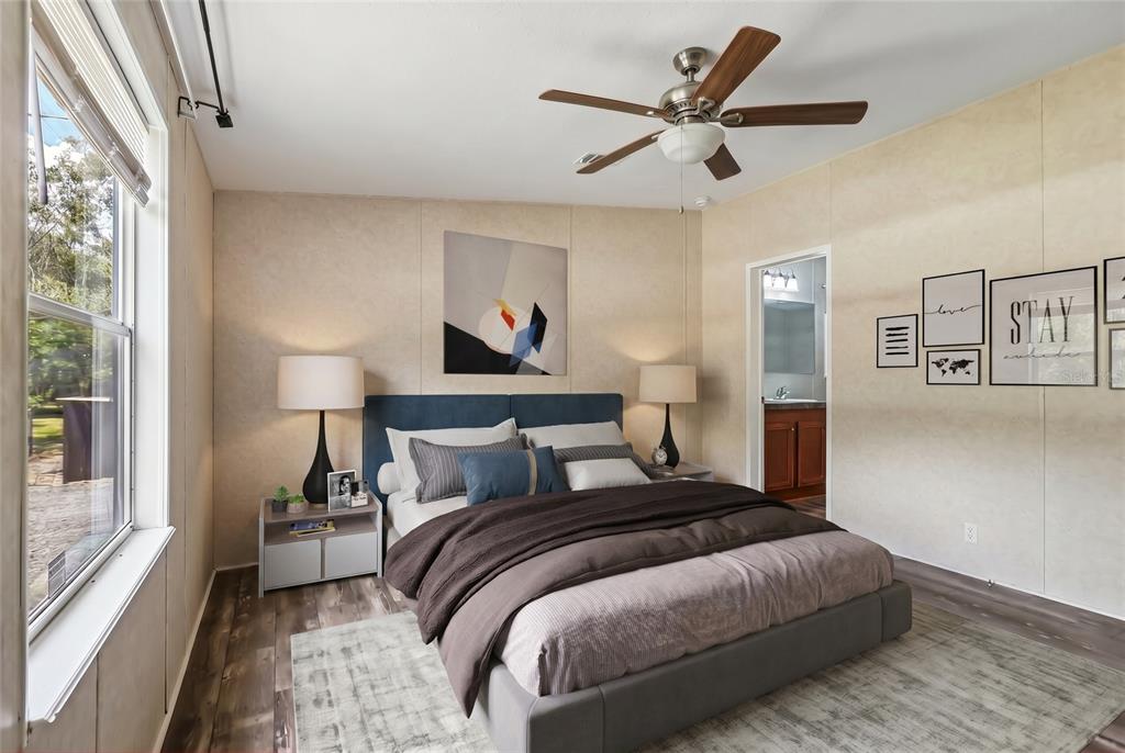 A bedroom features a blue upholstered bed, a ceiling fan, and wall-mounted artwork — 136 CREEKWOOD RUN, LAKELAND, FL