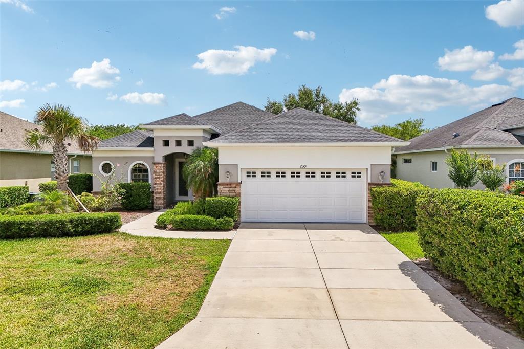 A single-story house with a white garage, stone accents, and a landscaped front yard — 259 DAHLIA COURT, BRADENTON, FL