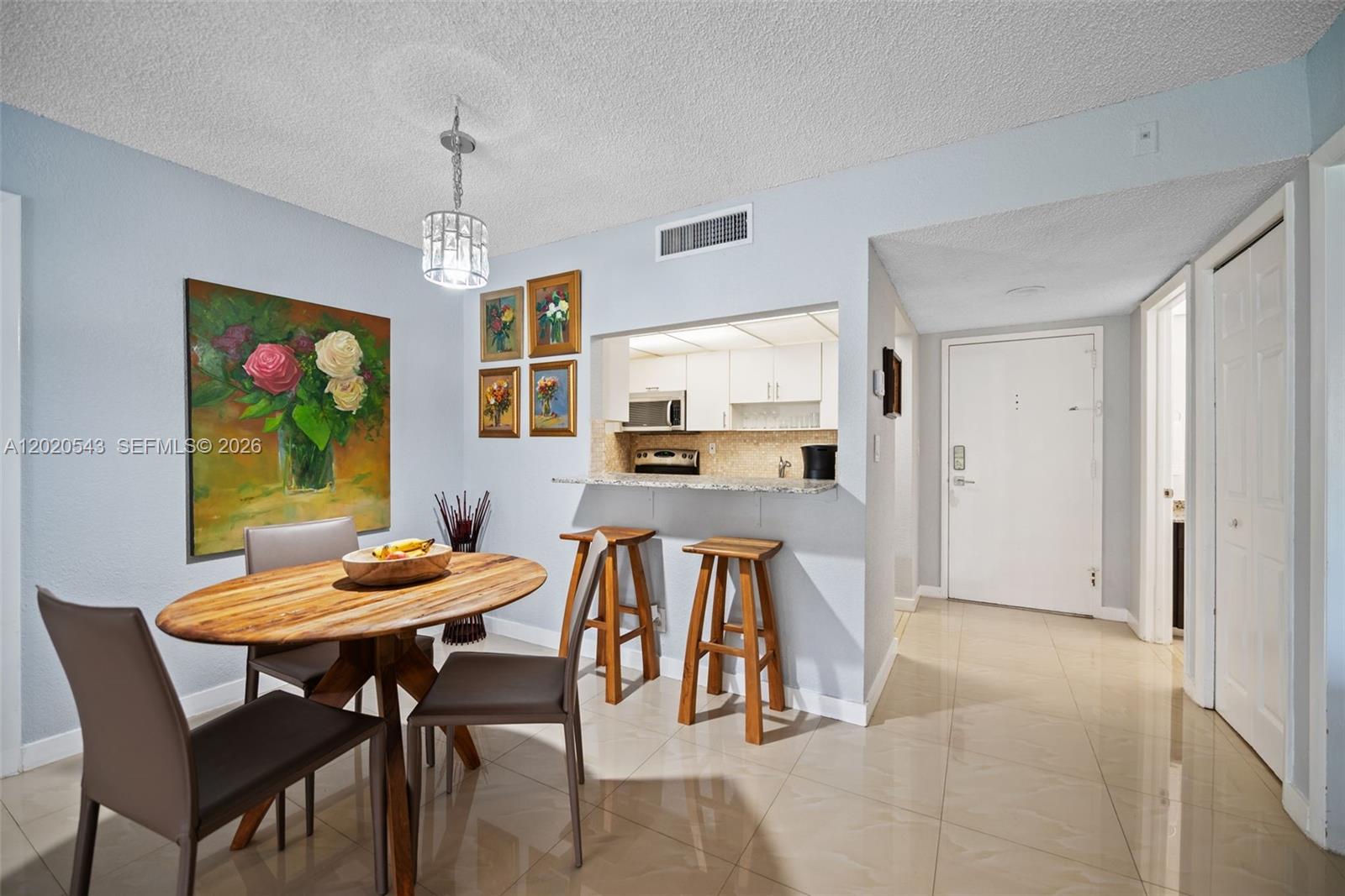 A dining area features a wooden table, bar stools at a pass-through window, and tile flooring — 200 Lakeview Dr # 113, Weston FL 33326, WESTON, FL
