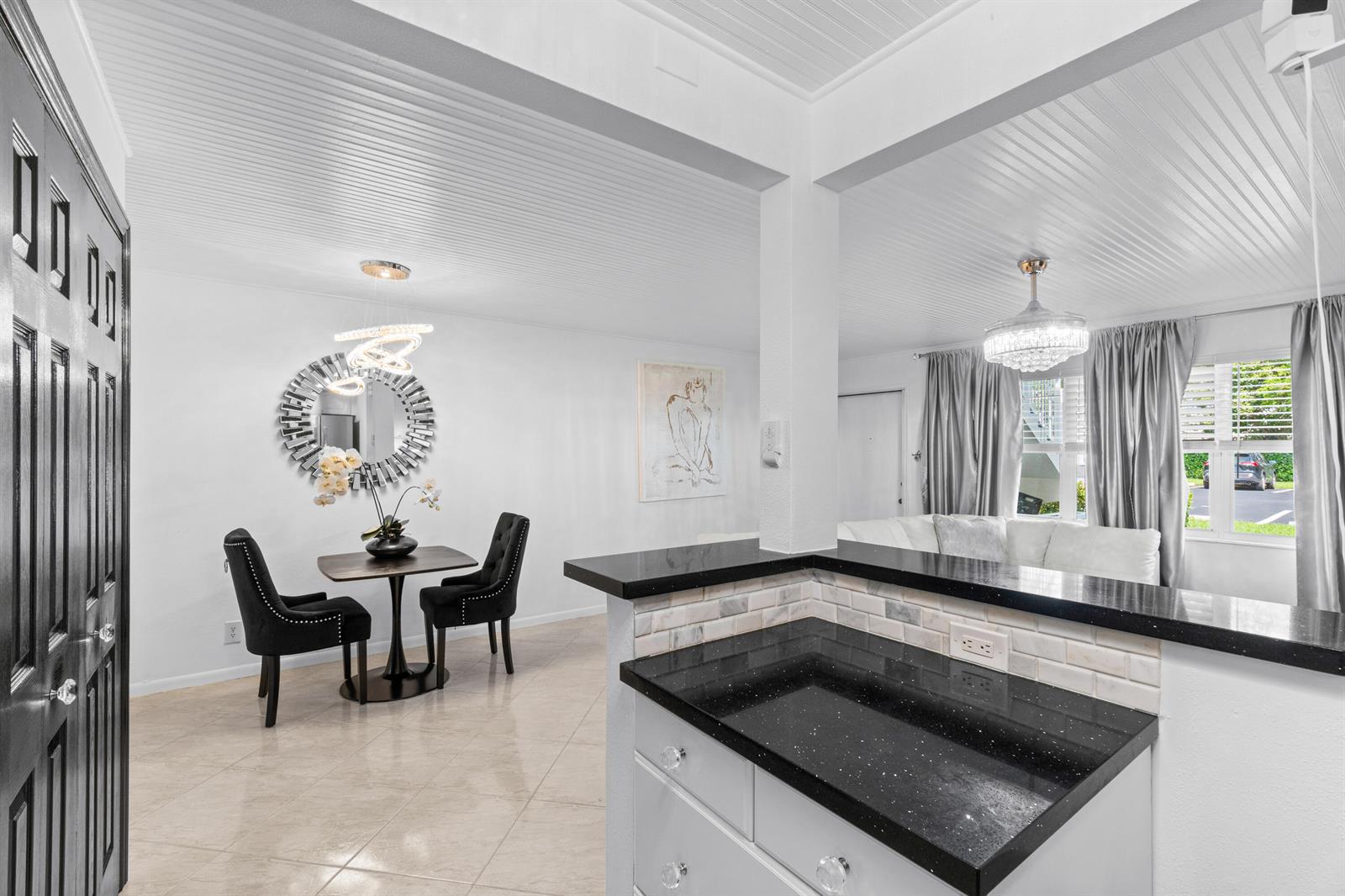 A dining area with a round mirror and two chairs sits beside a kitchen counter — 340 Horizons W # 102, Boynton Beach FL 33435, BOYNTON BEACH, FL