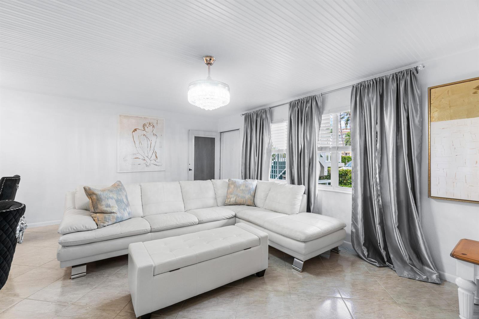 A living room features a white sectional sofa, a matching ottoman, and silver curtains — 340 Horizons W # 102, Boynton Beach FL 33435, BOYNTON BEACH, FL