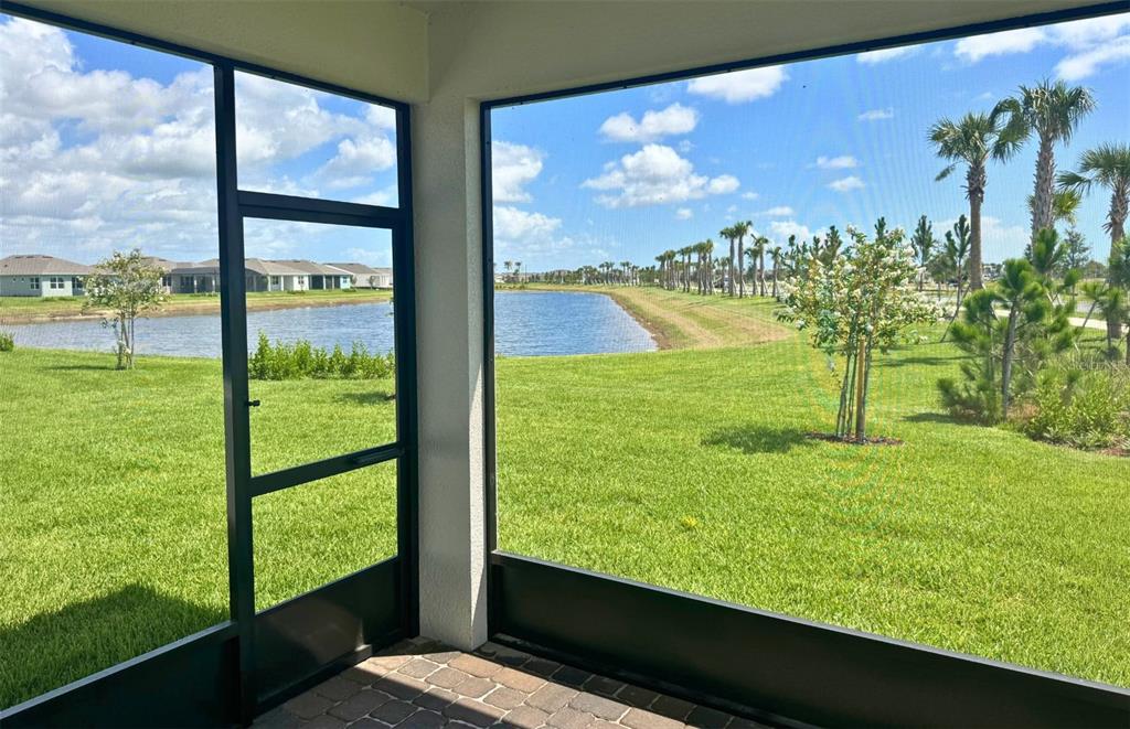 A screened-in patio overlooks a grassy lawn, a small pond, and palm trees — 9118 SERENADE DRIVE, MELBOURNE, FL