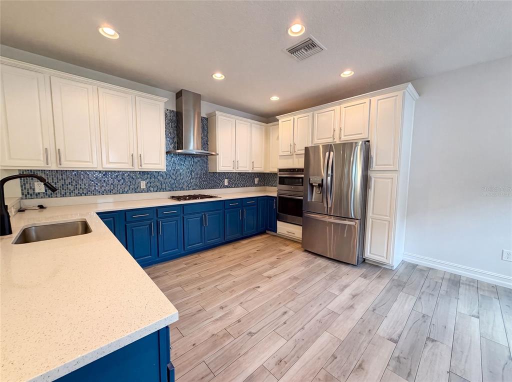 A kitchen features blue lower cabinets, white upper cabinets, stainless steel appliances, and tile flooring — 323 W LAMBRIGHT STREET, TAMPA, FL