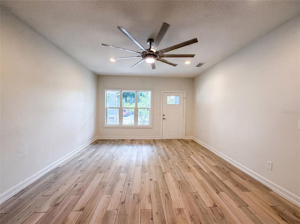 An empty room features light wood-look flooring, white walls, a ceiling fan, and a window — 323 W LAMBRIGHT STREET, TAMPA, FL