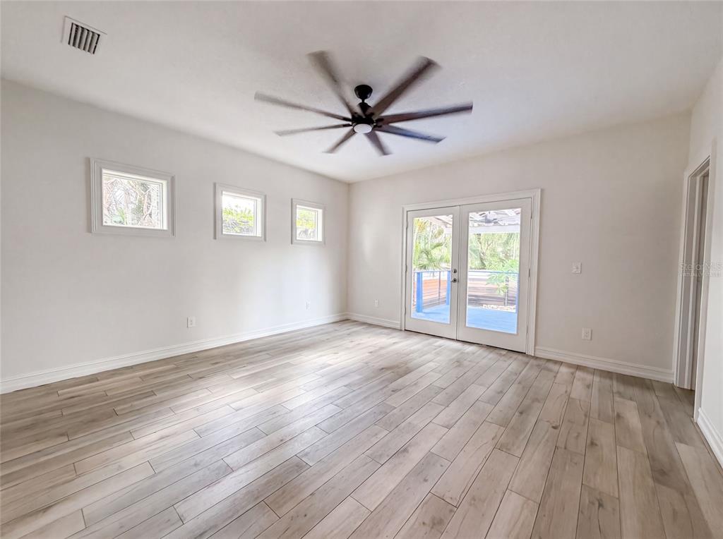 A bright room features light wood-look tile flooring, a ceiling fan, and glass patio doors — 323 W LAMBRIGHT STREET, TAMPA, FL