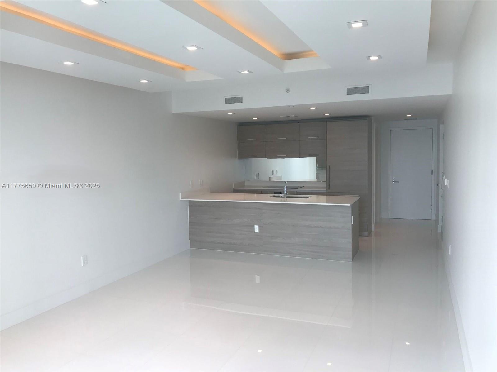 A modern kitchen features gray wood cabinetry, a white countertop island, and recessed ceiling lighting — 1300 S MIAMI AVE # 4003, Miami FL 33130, MIAMI, FL