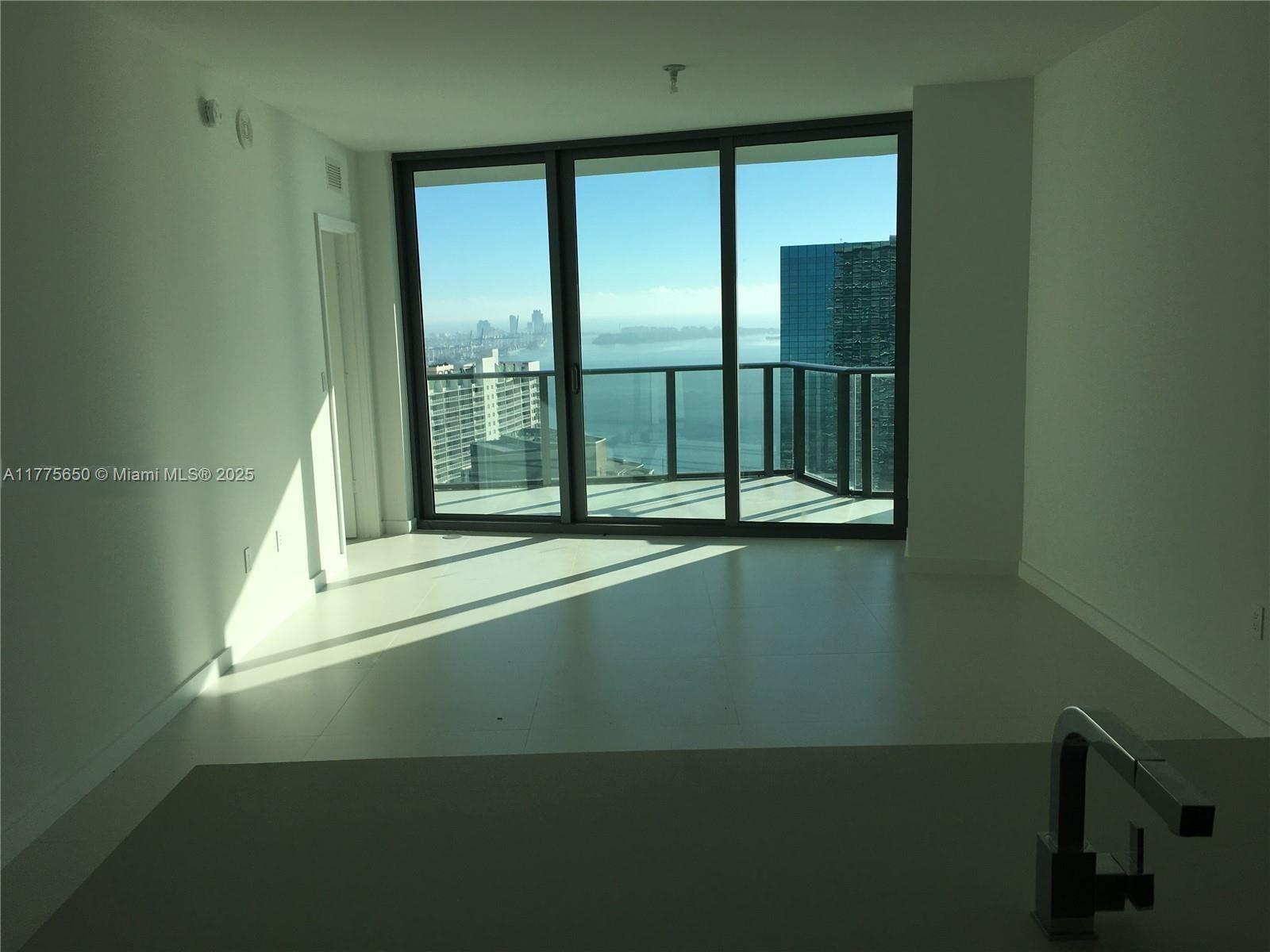An empty room features white tile floors, a modern kitchen faucet, and a balcony overlooking water — 1300 S MIAMI AVE # 4003, Miami FL 33130, MIAMI, FL