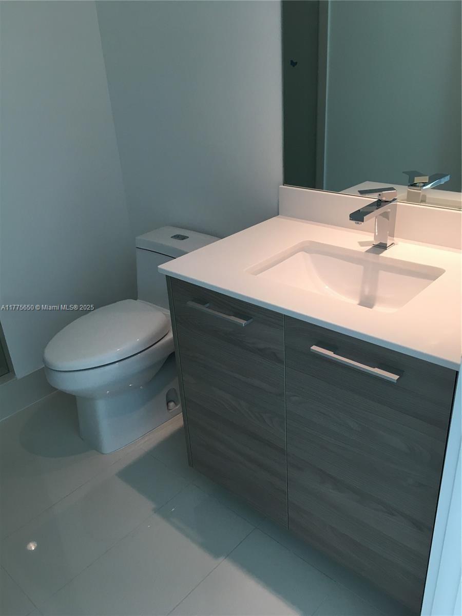A modern bathroom features a white vanity with a sink and a white toilet — 1300 S MIAMI AVE # 4003, Miami FL 33130, MIAMI, FL