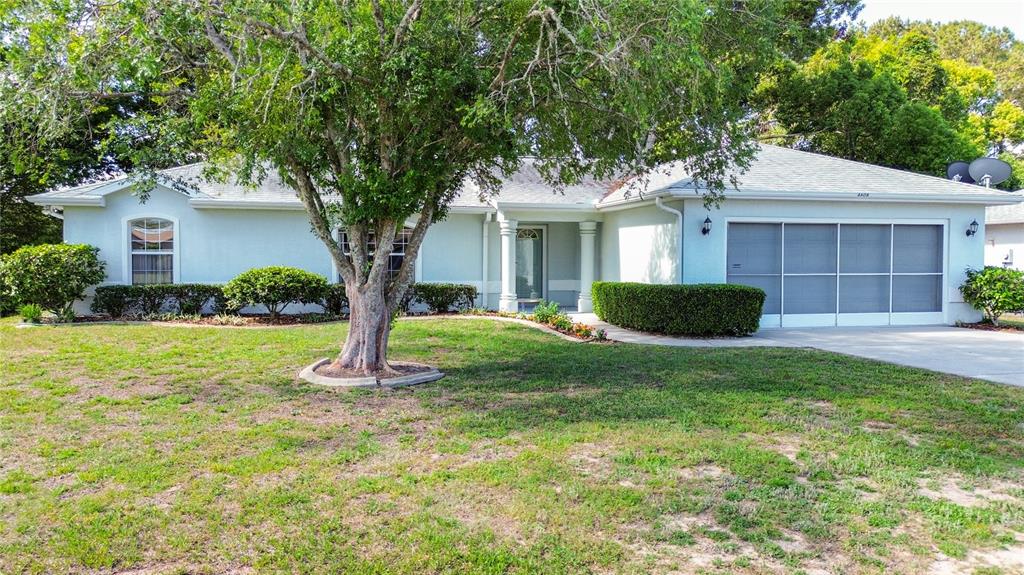 A single-story house with a light-colored exterior, a two-car garage, and a large front tree — 4608 NW 30TH PLACE, OCALA, FL