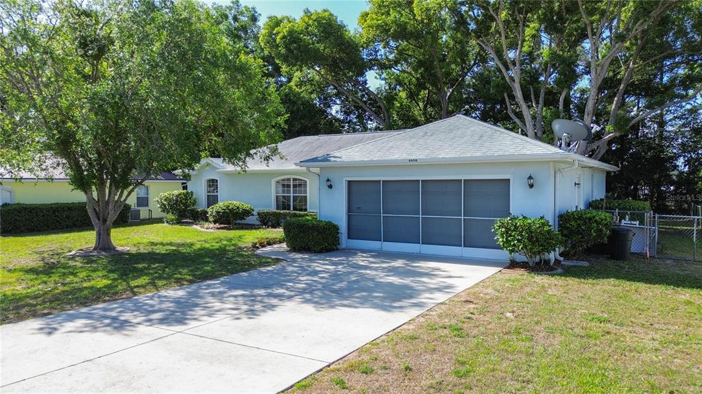 A single-story house with a screened-in garage and a concrete driveway surrounded by trees — 4608 NW 30TH PLACE, OCALA, FL