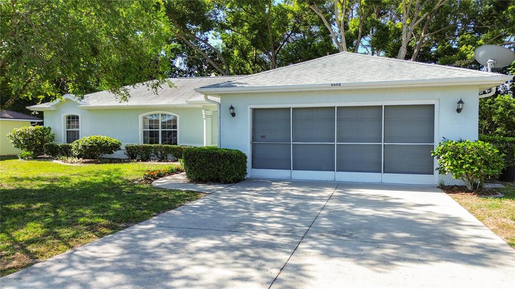 A light-colored single-story house features a screened-in garage and a concrete driveway — 4608 NW 30TH PLACE, OCALA, FL
