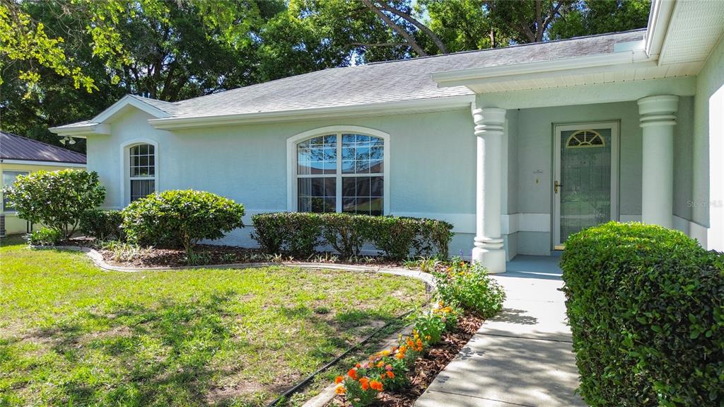 A light blue, single-story house features a front porch with white columns and landscaping — 4608 NW 30TH PLACE, OCALA, FL