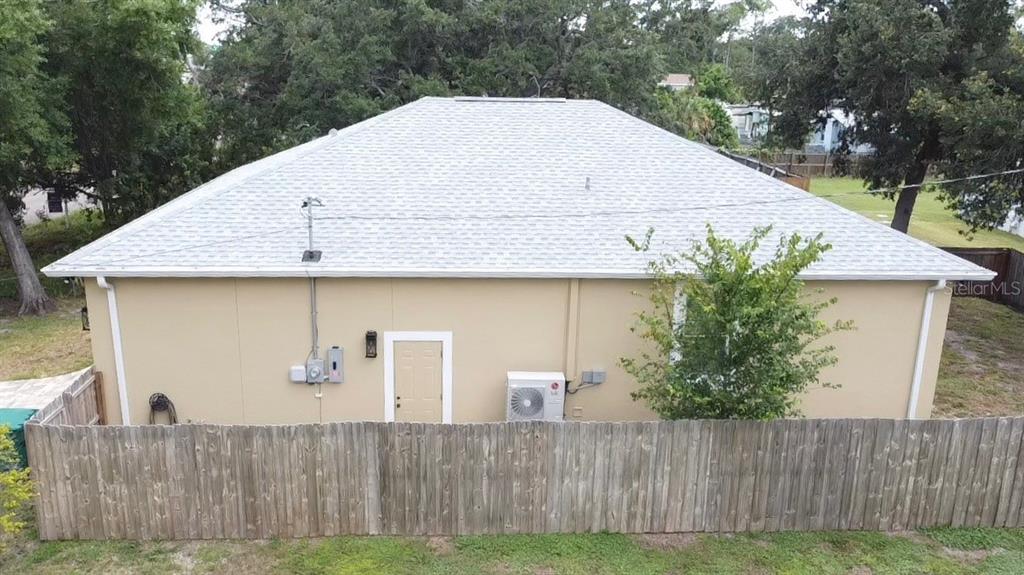 The exterior of a tan house features a light-colored shingled roof and a wooden fence — 3225 LAUREL AVENUE, CLEARWATER, FL