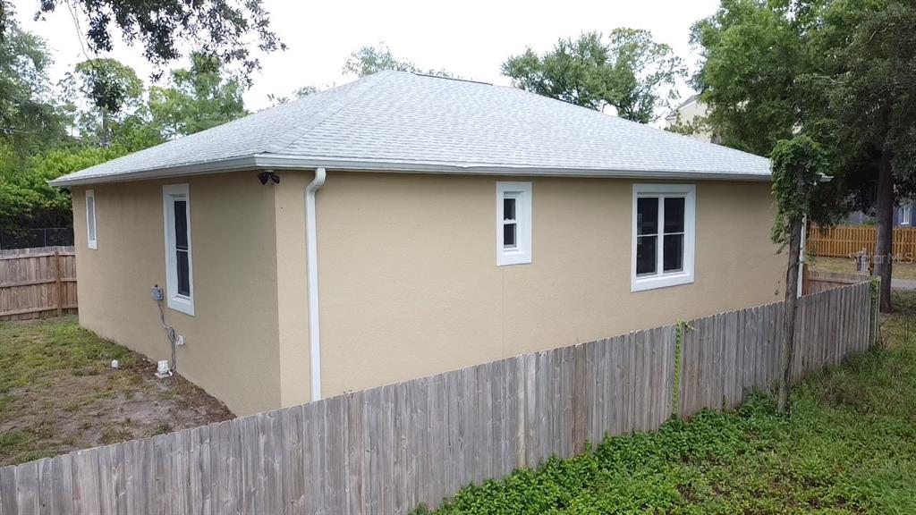 A tan stucco house with a gray hip roof and white-trimmed windows behind a fence — 3225 LAUREL AVENUE, CLEARWATER, FL