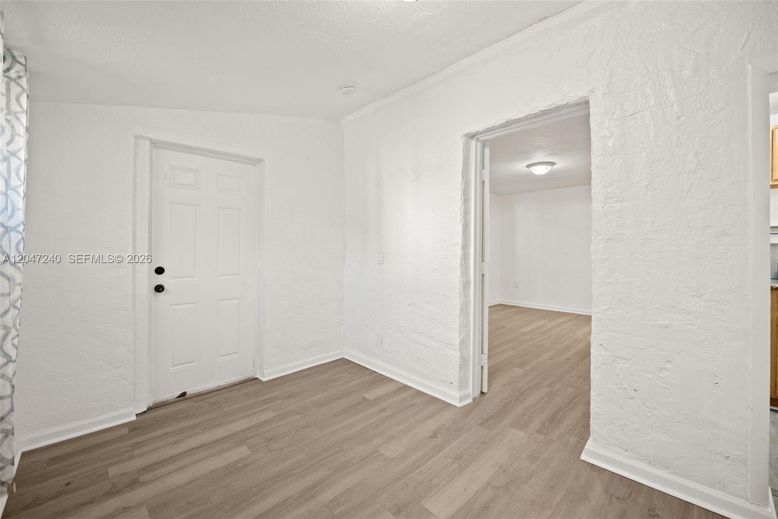 An interior view shows a white room with a door and an arched doorway — MIAMI, FL