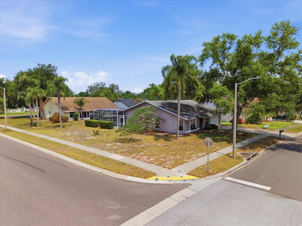 An exterior view of a single-story house on a corner lot with a screened pool — 798 COUNTRYSHIRE LANE, PALM HARBOR, FL