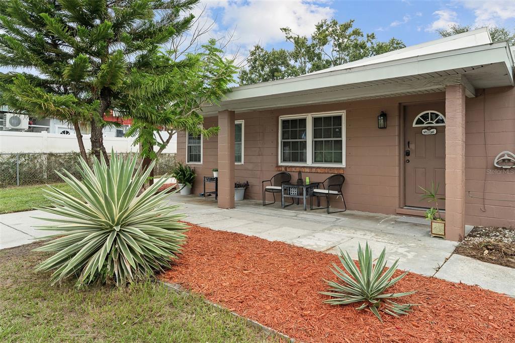 A single-story house with a brown concrete block exterior, a covered porch, and landscaping — 2309 W CLUSTER AVENUE, TAMPA, FL