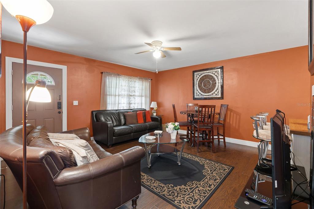 A living and dining room with orange walls, dark leather furniture, and hardwood floors — 2309 W CLUSTER AVENUE, TAMPA, FL