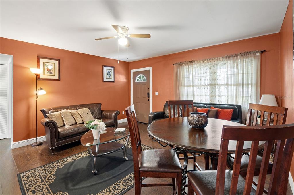 A living and dining room with orange walls, wood floors, a ceiling fan, and furniture — 2309 W CLUSTER AVENUE, TAMPA, FL