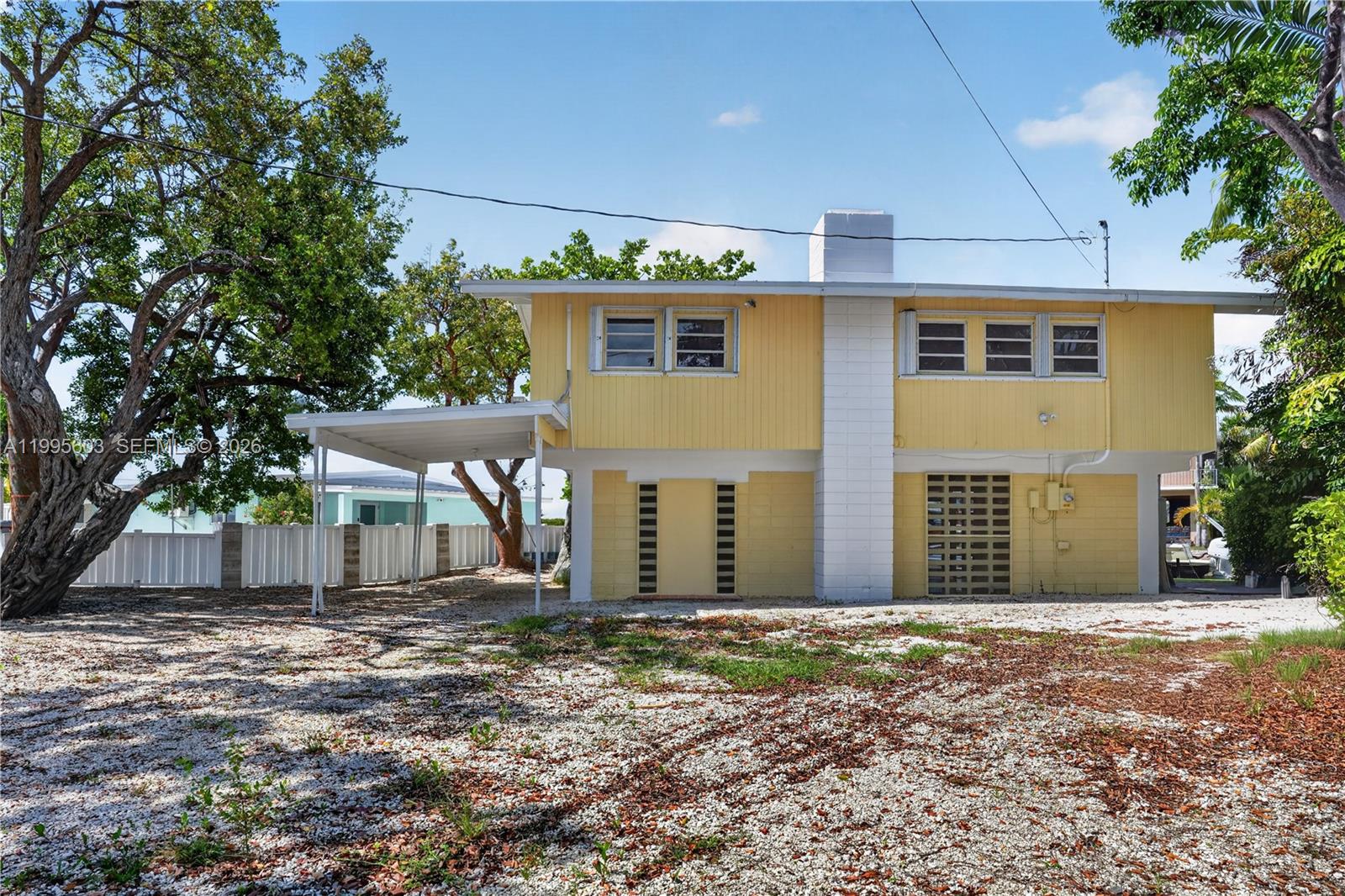 A yellow two-story house with a carport and a gravel yard — 1126 Grand St, Key Largo FL 33037, KEY LARGO, FL