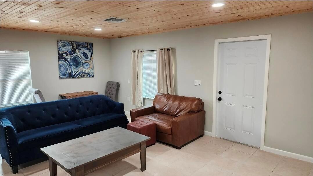 A living room features a blue tufted sofa, brown leather chair, and wood-paneled ceiling — 618 Hunter Street, West Palm Beach FL 33405, WEST PALM BEACH, FL