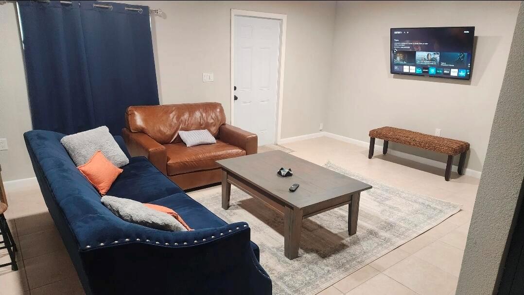 A living room features a blue sofa, a brown leather chair, and a wall-mounted television — 618 Hunter Street, West Palm Beach FL 33405, WEST PALM BEACH, FL