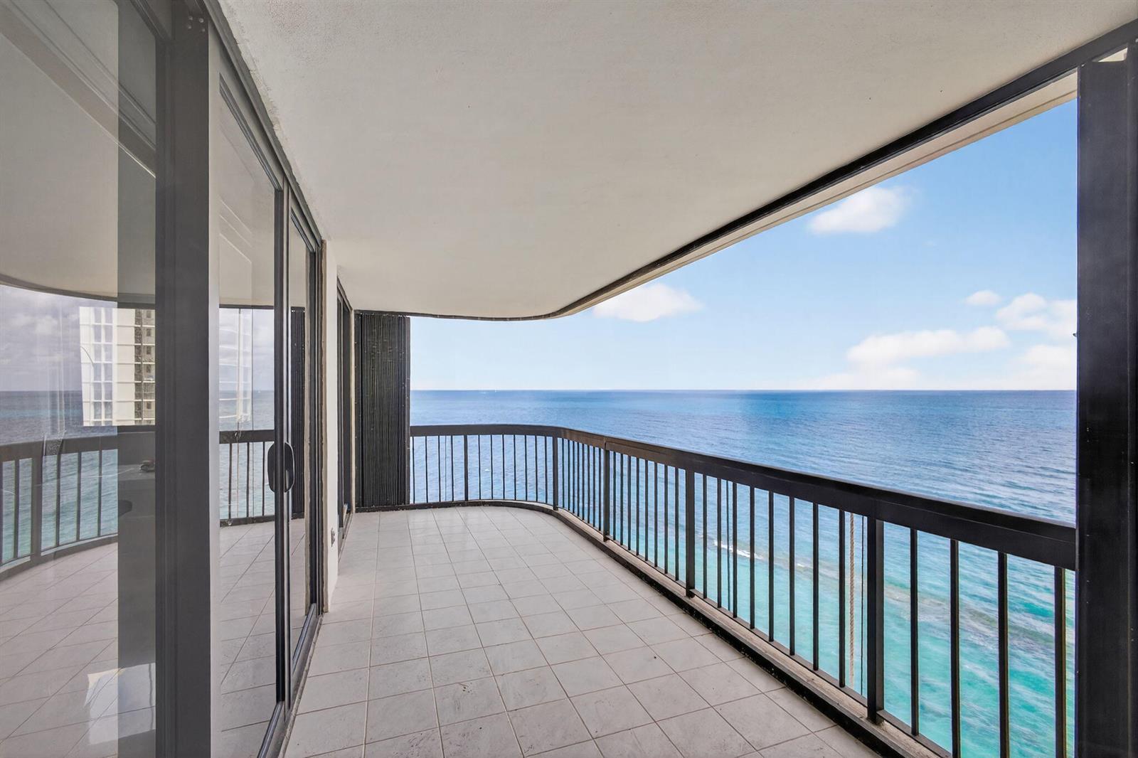 A tiled balcony with a black metal railing overlooks the ocean under a blue sky — 5380 N Ocean Drive # 12e, Singer Island FL 33404, SINGER ISLAND, FL