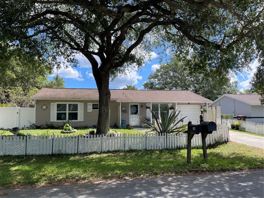 A single-story house with a white picket fence, a large tree, and a mailbox — 35 HICKORY TRACK WAY, OCALA, FL