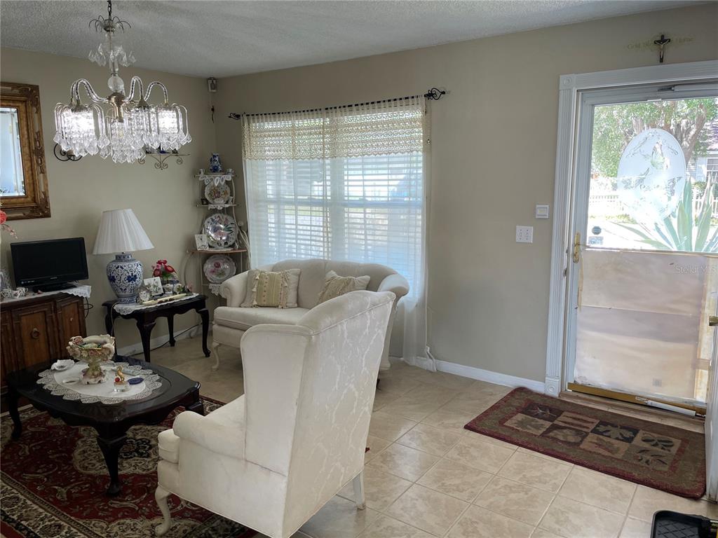 A living room features tile flooring, a crystal chandelier, a white sofa, and an entryway — 35 HICKORY TRACK WAY, OCALA, FL