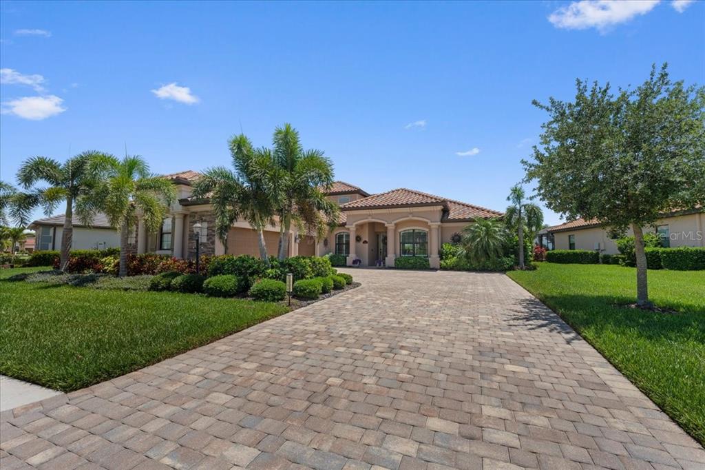 A single-story house with a paved driveway, palm trees, and a tiled roof — 5580 MULLIGAN WAY, LAKEWOOD RANCH, FL