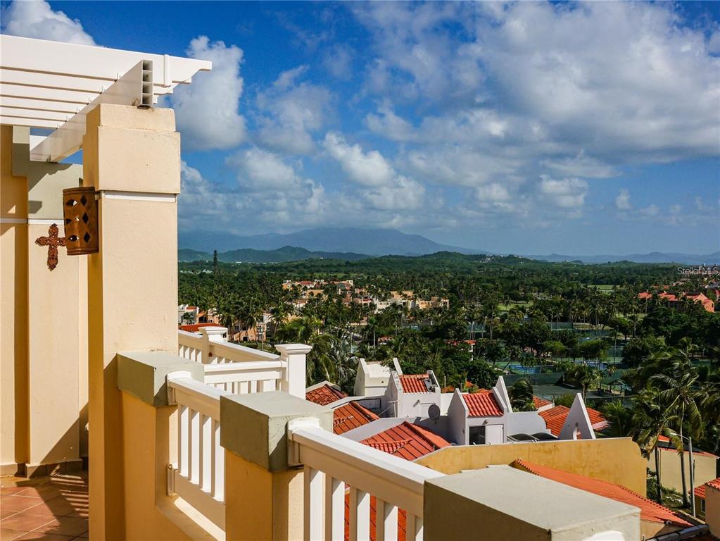 A balcony with a white railing overlooks a tropical landscape with mountains in the distance — 285 PALMAS INN DRIVE UNIT 8-302, HUMACAO, PR