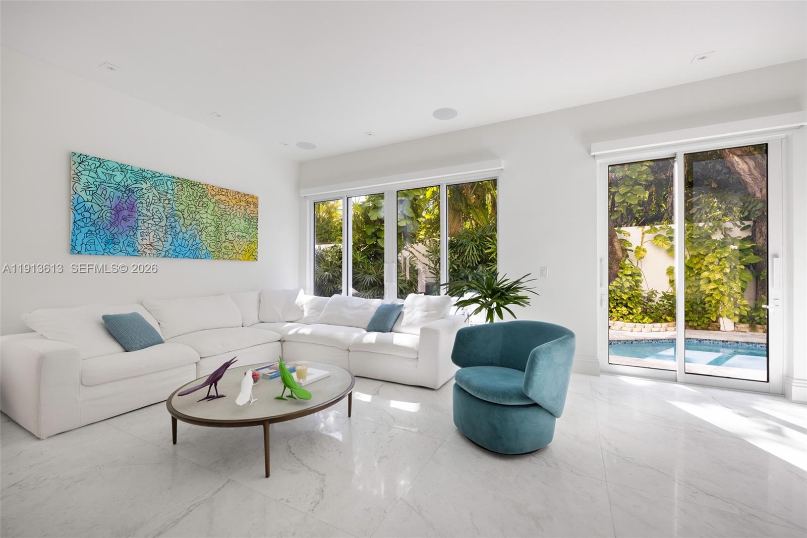 A bright living room features a white sectional sofa, blue accent chair, and pool view — 2760 Brickell Ct # 2760, Miami FL 33129, MIAMI, FL