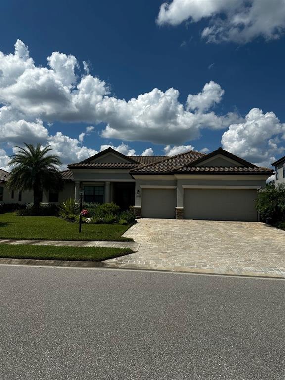 A single-story house with a tiled roof, two garage doors, and a paved driveway — 17025 POLO TRAIL, BRADENTON, FL